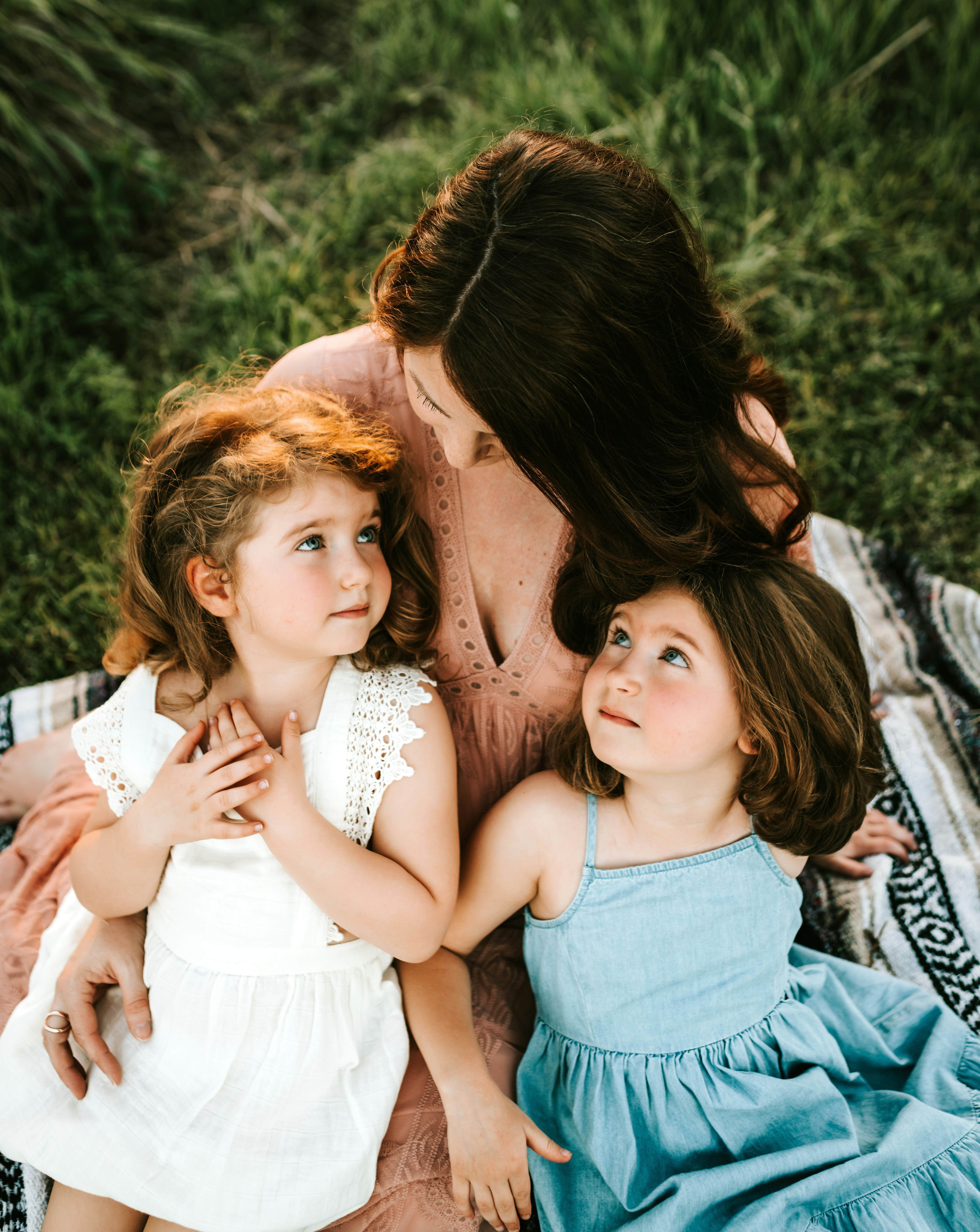 Loving mother with her two young daughters in a tender family moment outdoors, representing the nurturing parent-child relationships that DEFUZE Family helps protect and support